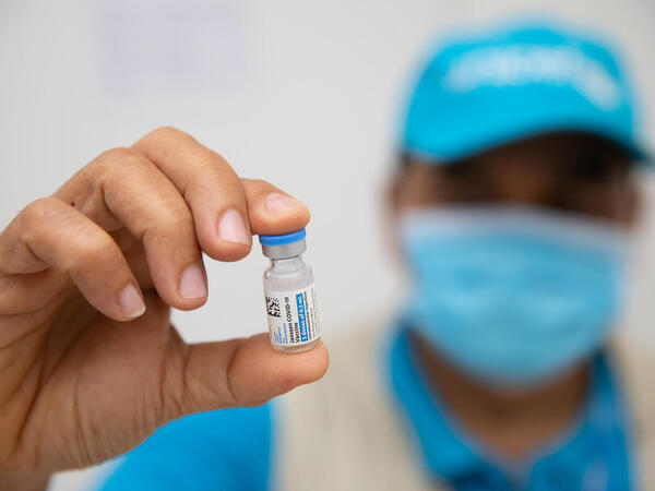 a UN-clad masked worker holds up a vial