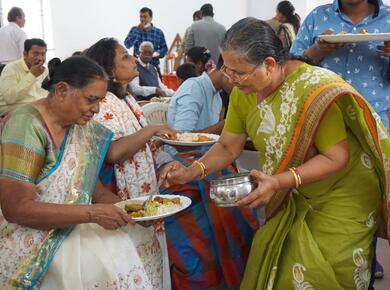 two women in colourful saris serve each other food