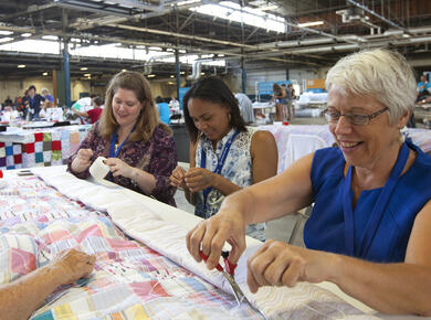 women gathered around a quilt