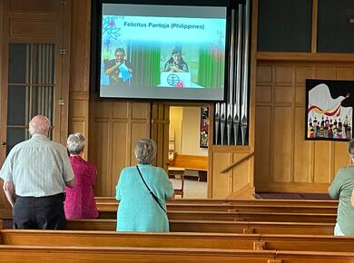 people in pews watch a video on screen