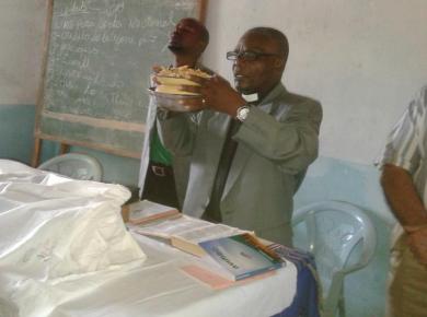 <p>Evangelist Laston Bissani prays for the Communion bread. Photo: courtesy of Laston Bissani.</p>