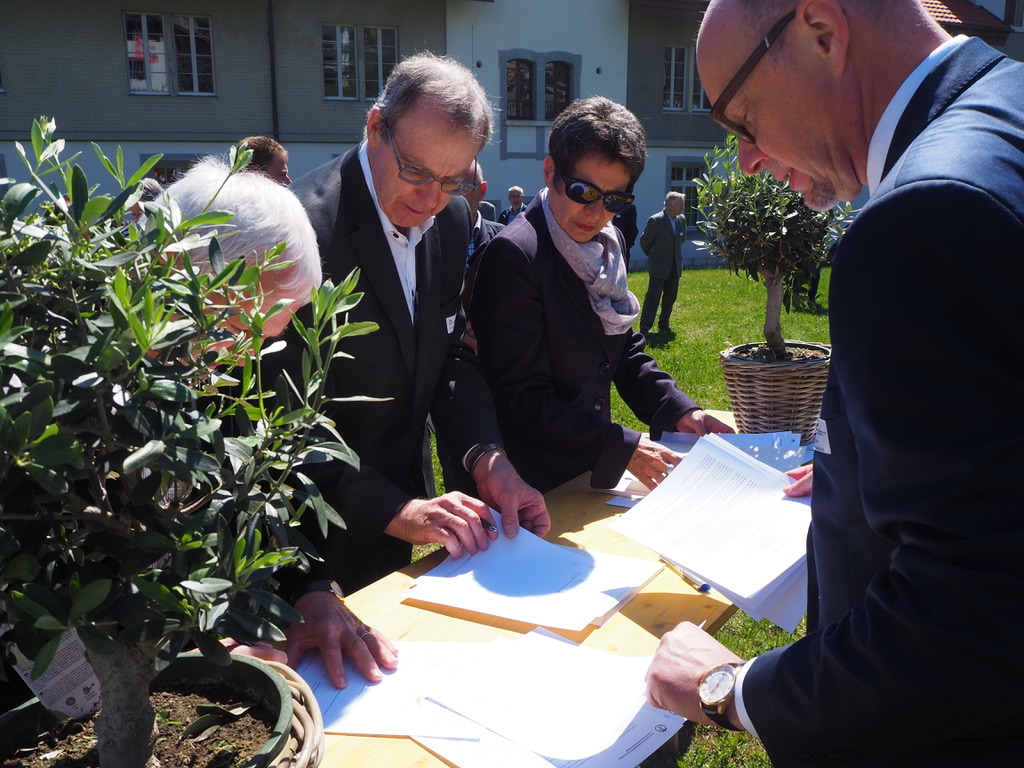 Delegates from KMS/CMS congregations (from left, Karl Martin of Schänzli, Ernest Geiser of Tavannes and Nelly Gerber-Geiser of Sonnenberg) sign a declaration of forgiveness 20 April 2019 as general secretary Jürg Bräker, right, observes. Photo: Raphaël Burkhalter